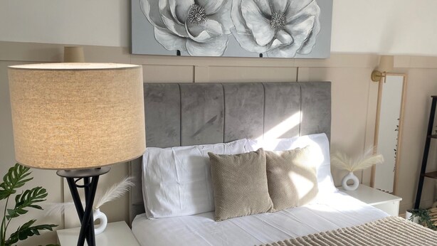 A neatly arranged bedroom with a bed, a bedside lamp, a nightstand, and a wall-mounted painting. - Traditonal House - Etihad -Games Room-Free Parking (Manchester)