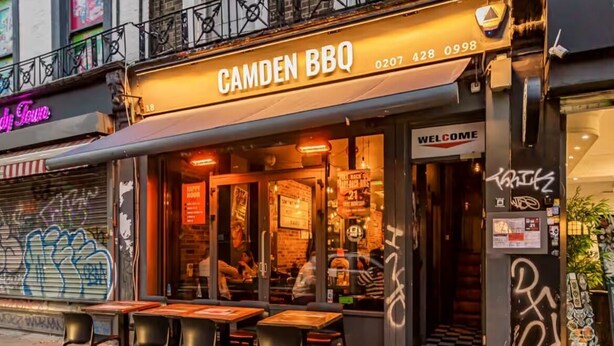 Un restaurant appelé « Camden BBQ » qui dispose d’une terrasse et d’une enseigne au néon.