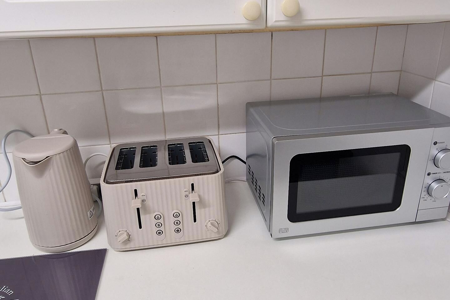 Een keuken met een broodrooster, een waterkoker en een magnetron.