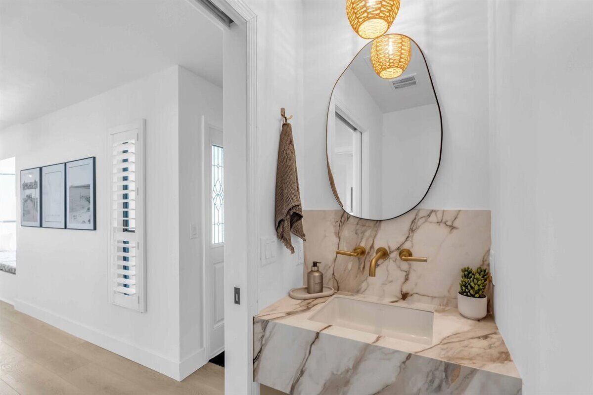Une salle de bain moderne avec un lavabo en marbre, des robinetteries dorées et un grand miroir.