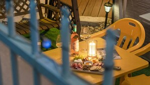 An outdoor dining area with a table set for two, featuring a bottle of wine, glasses, a candle, and a selection of cheeses, meats, and crackers. - Gapyeong Gabom Kids Poolvilla Pension (Gapyeong)