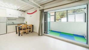 Una cocina moderna con zona de comedor, puerta corrediza de vidrio a un balcón y vistas a zonas verdes.