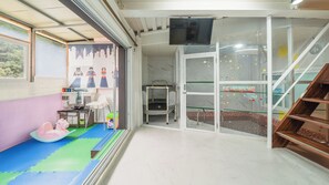 Une salle de jeux pour enfants avec un parc, des jouets et un téléviseur.