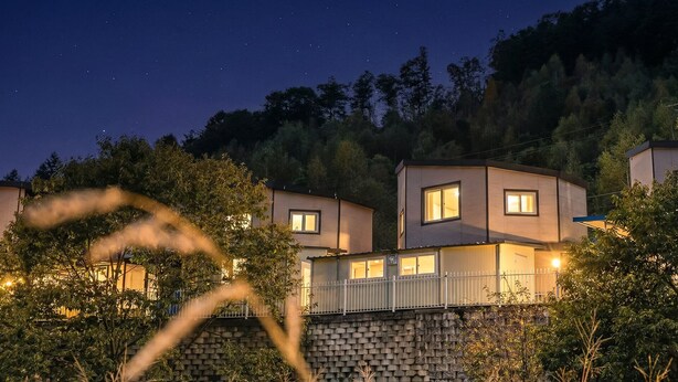 A modern two-story house with a stone retaining wall, multiple windows, and a balcony. - Gapyeong Gabom Kids Poolvilla Pension (Gapyeong)