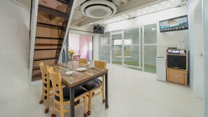 A dining area with a wooden table and chairs, a television mounted on the wall, and a refrigerator with a control panel. - Gapyeong Gabom Kids Poolvilla Pension (Gapyeong)