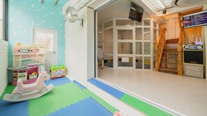 Un área de juegos infantiles con una cocina de juguete, un caballo balancín y un tapete de juego.