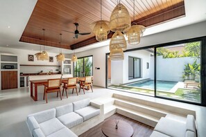 Un salon moderne doté d’un grand canapé, d’un coin repas et offrant une vue sur une piscine.