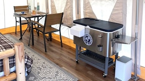 Een tent met een grill, stoelen en een tafel.