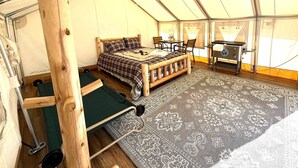 Een tent met een bed, een tafel, stoelen en een kleine kitchenette.