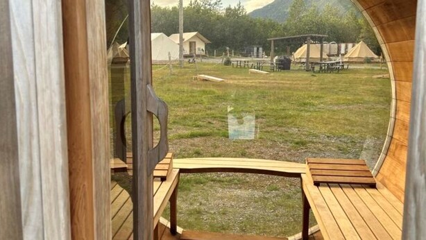 Houten interieur met uitzicht op een gazon, banken en een heldere lucht.