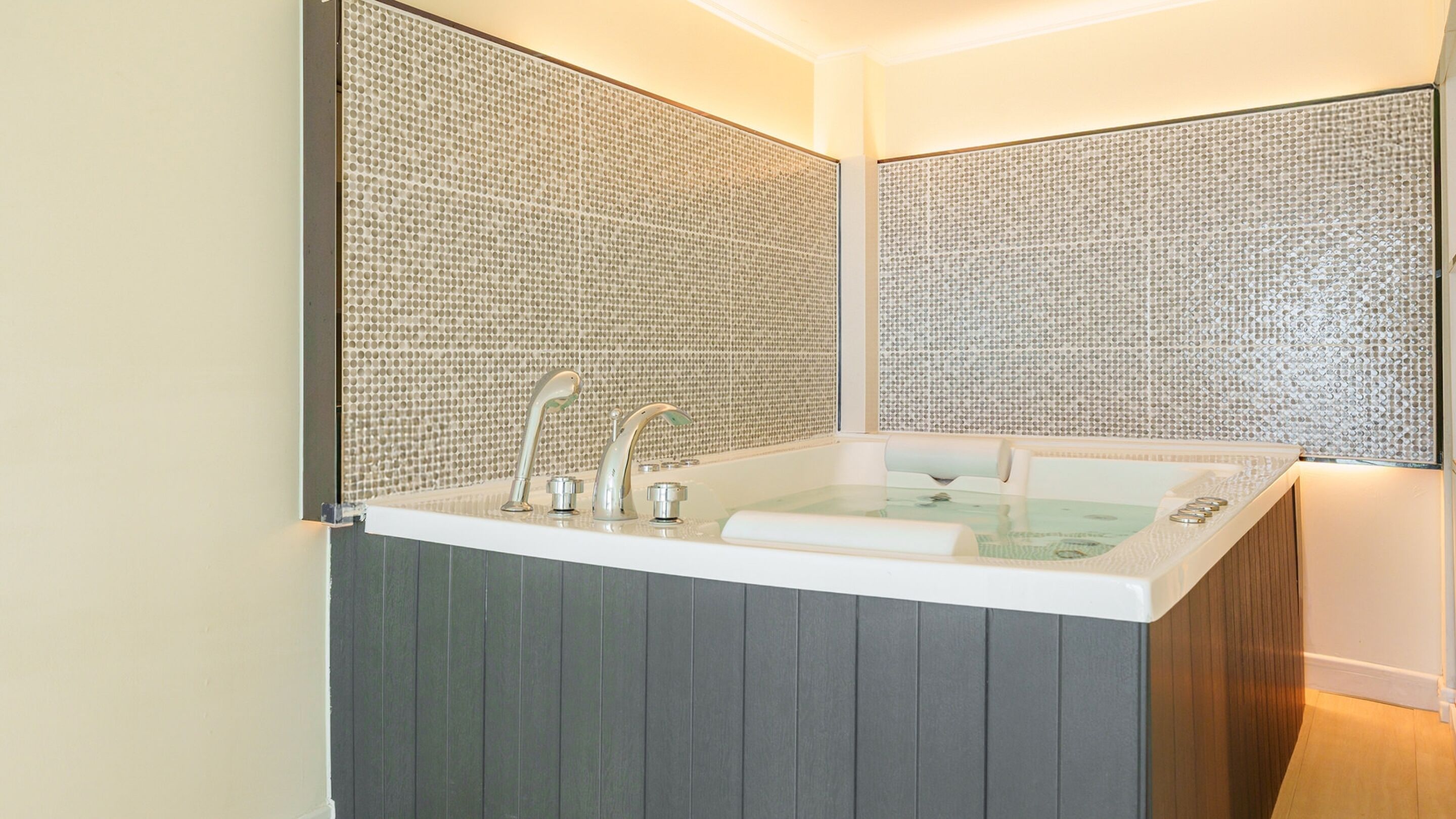 Een moderne badkamer met een vrijstaand bad, een dubbele wastafel en een decoratief wandpaneel.