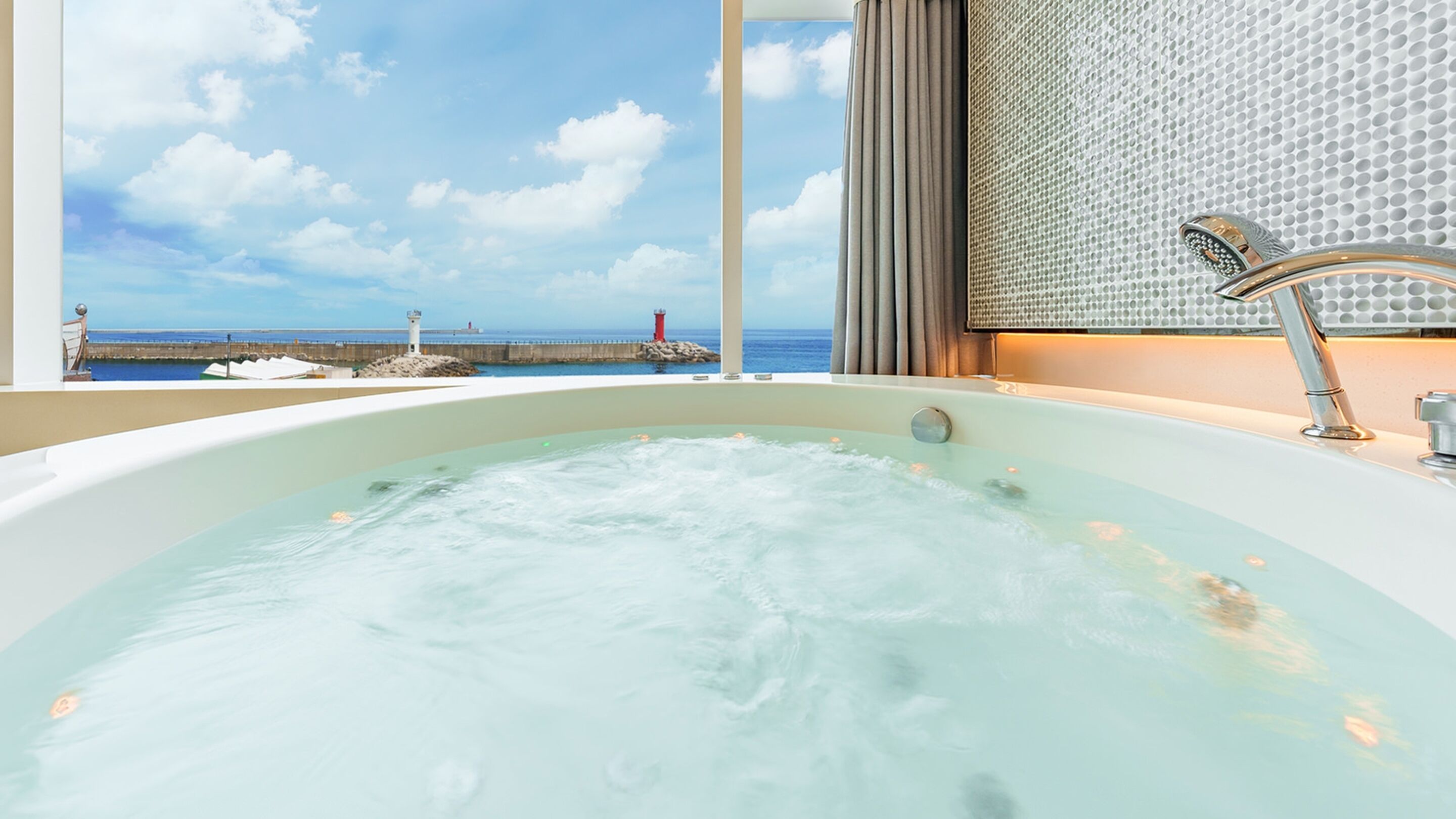 Eine Badewanne mit Blick auf das Meer und einen Leuchtturm.