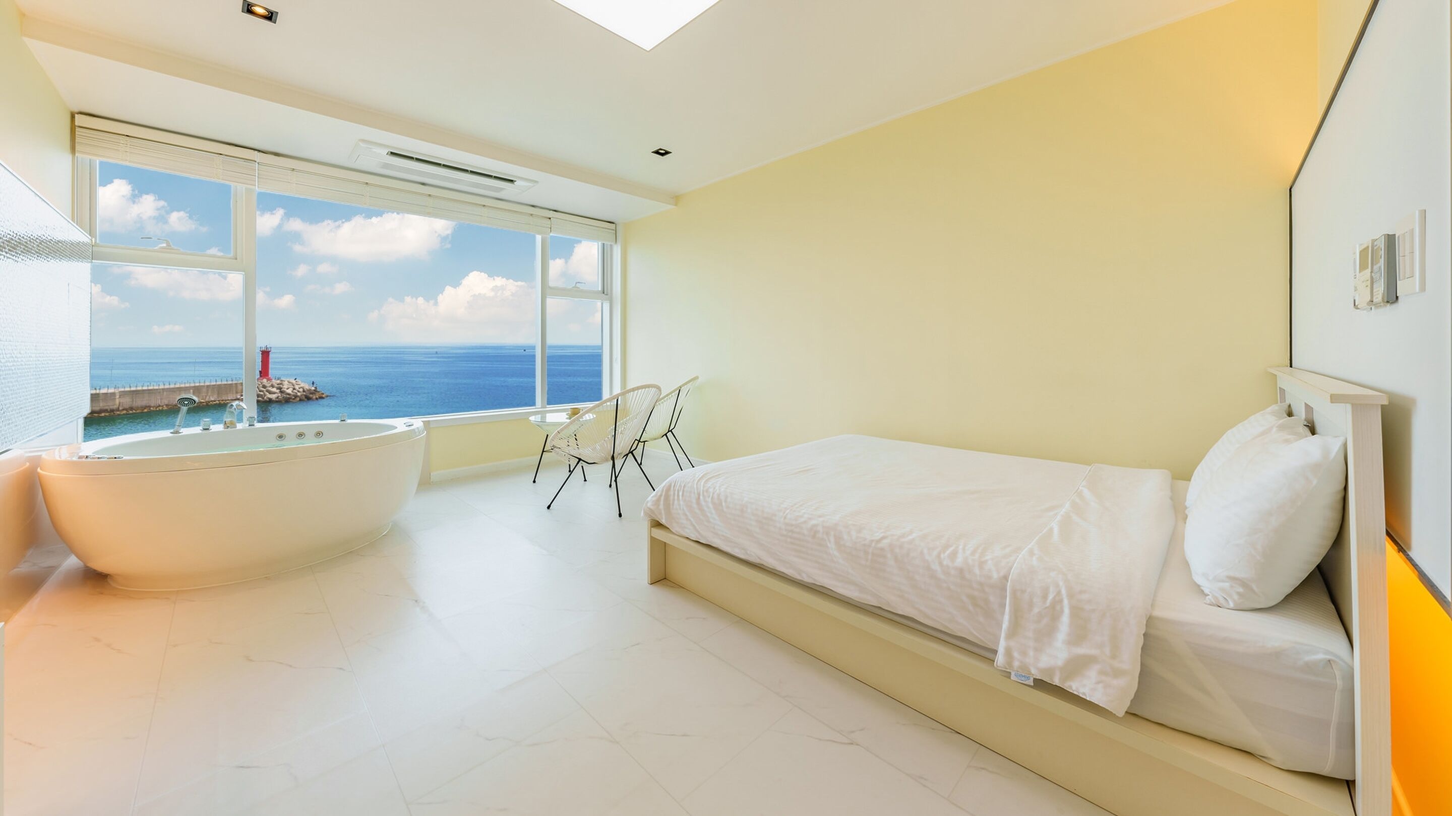 A modern bedroom with a large window, a bathtub, and a bed.