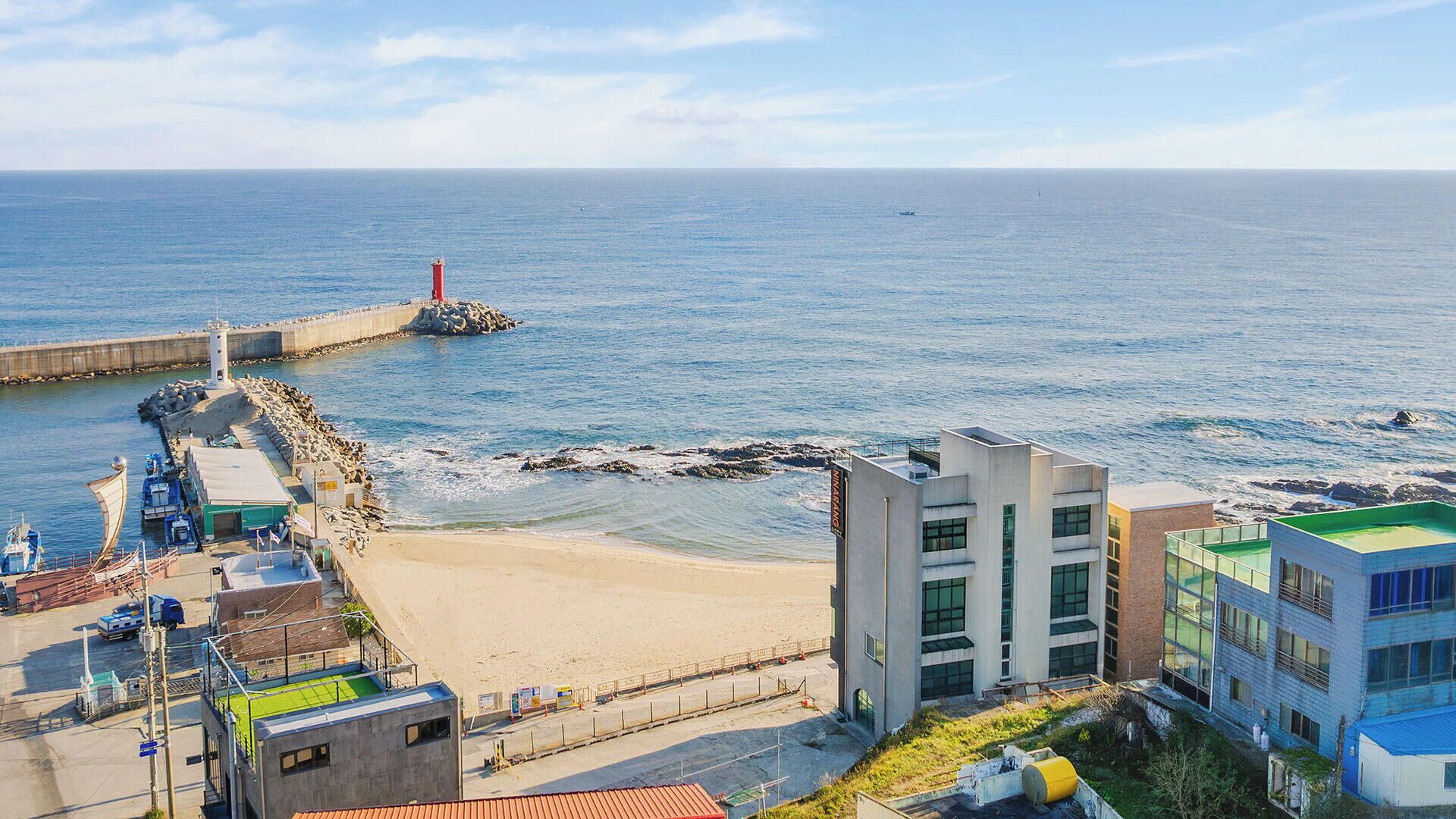 Vista costeira com farol, praia e edifícios.