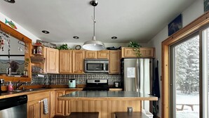 Eine moderne Küche mit Holzausstattung, einer zentralen Kochinsel mit Sitzgelegenheiten, einer Mikrowelle und einem Kühlschrank.