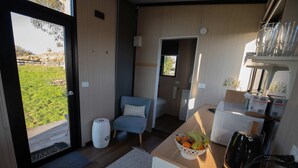 A compact kitchen with a sink, a microwave, and a fruit basket on the counter.