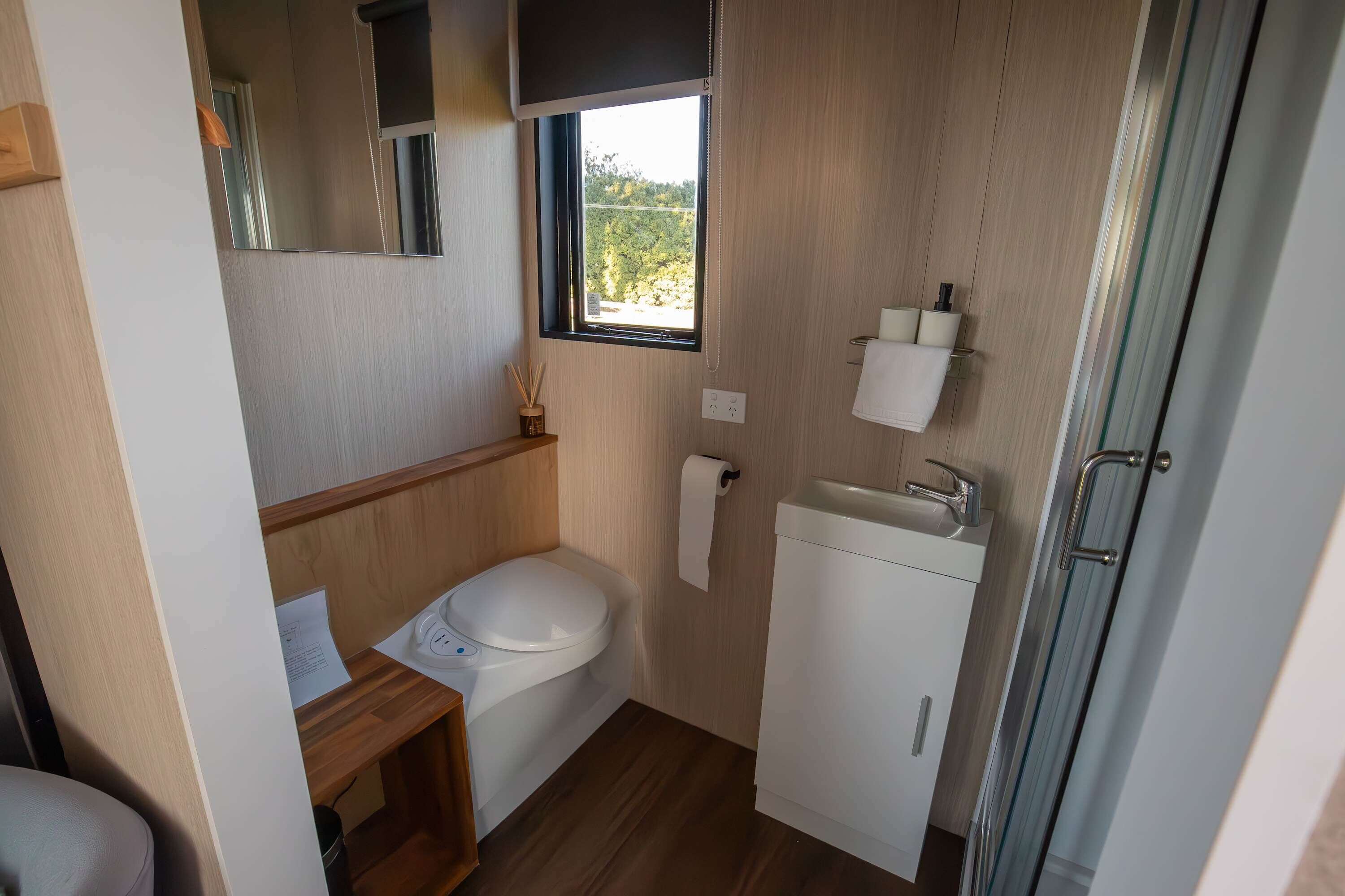 Une petite salle de bain comprenant des toilettes, un lavabo et une petite fenêtre.