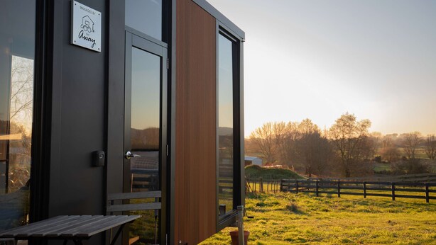 A modern building with a wooden door and a sign that reads "Managed by Away."