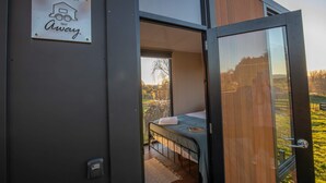 A modern, compact room with a bed, a small window, and a sign indicating management by 'Tiny Away'.