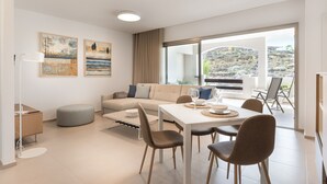 Ein modernes Wohnzimmer mit einer Couch, einem Esstisch, Stühlen und Kunstwerken an den Wänden.