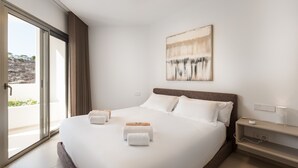 Ein Hotelzimmer mit einem großen Bett, einem Nachttisch mit Lampe und Blick ins Freie.