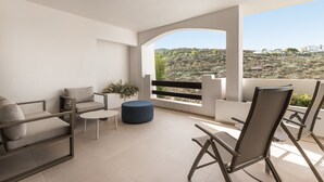 Ein Balkon mit einer Couch, Stühlen, einem kleinen Tisch und einem Blumentopf.