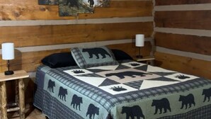 A log cabin bedroom with a bed, two bedside lamps, and a forest-themed wall hanging. - Charming 3-bedroom 5 bed hottub cabin WiFi in scenic Seneca Rocks West Virginia (Seneca Rocks)