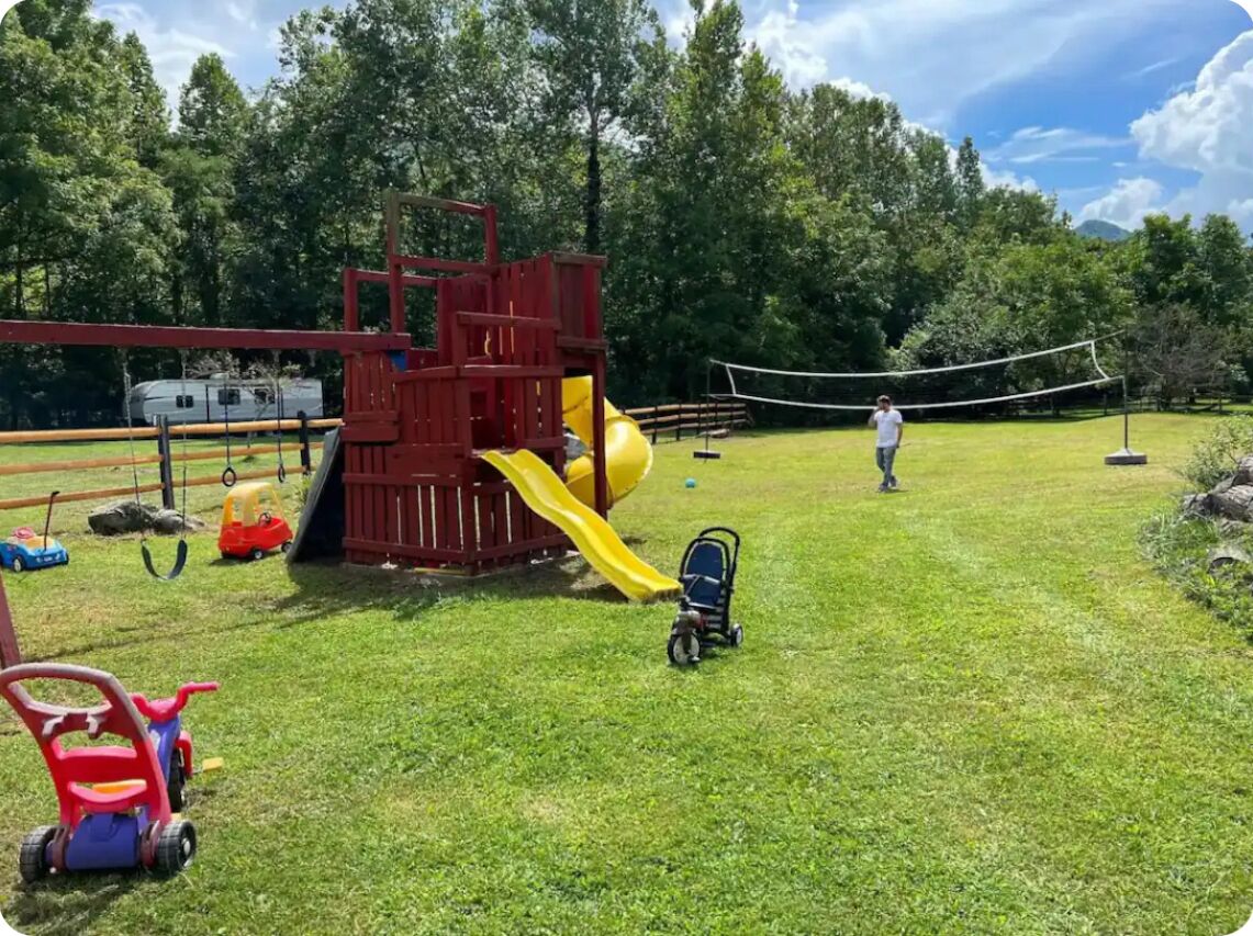 A playground with a slide and swings, a volleyball net, and a stroller.