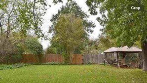 A backyard with a wooden fence, a tree, and a covered outdoor seating area. - Charming 3-bedroom house with WiFi, AC in lovely Wichita Falls (Wichita Falls)