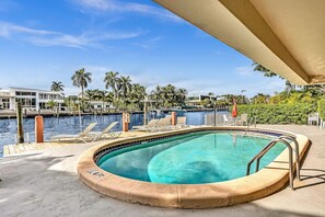A swimming pool with a view of a marina and palm trees. - Bay Harbor Sunset Apt 3A (Bay Harbor Islands)