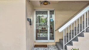 Un escalier menant à une porte sur laquelle est apposée une pancarte indiquant « MASQUES », un hall d’entrée carrelé et une petite plante près de la porte.