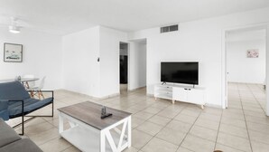 Un salon moderne avec un téléviseur à écran plat, une table basse et un canapé.