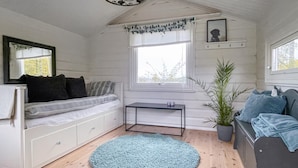 Une pièce confortable avec un lit, une petite table, une fenêtre donnant sur un beau paysage, une plante et un miroir au mur.