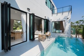A modern house with an outdoor swimming pool, large glass doors, and a dining area with wicker furniture. - Lyntara Pool Villa Nongkhai (Nong Khai)