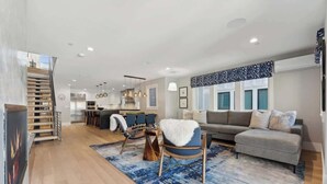 Un salon moderne avec un canapé, des fauteuils, un tapis et un escalier.