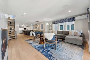 Un salon moderne avec un canapé, des fauteuils, un tapis et un escalier.