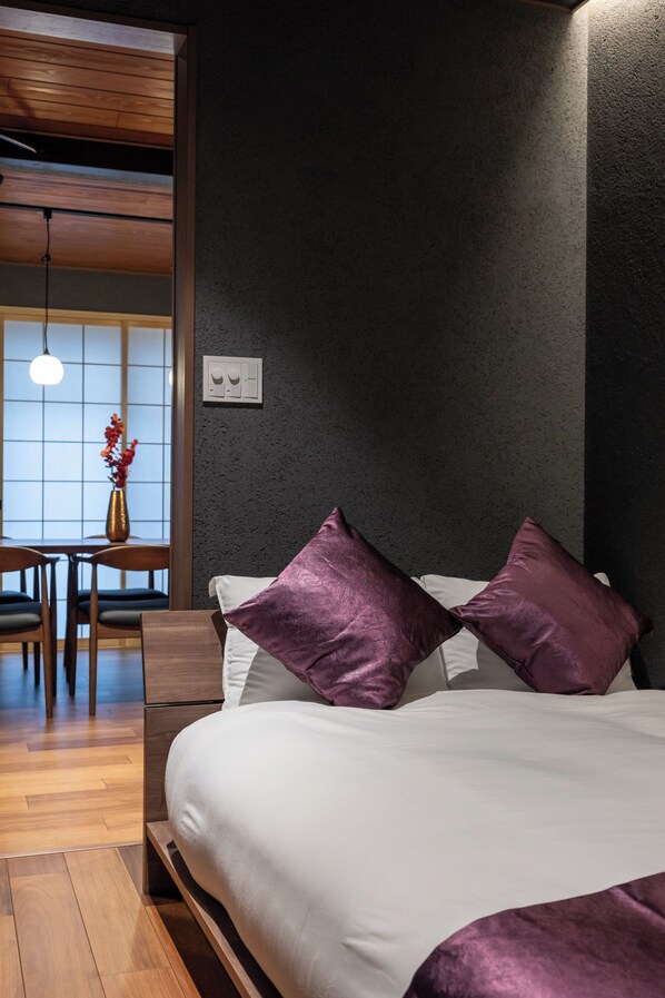 Une chambre à coucher moderne avec une tête de lit en bois, un lit blanc et deux oreillers violets.