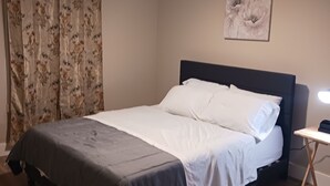 Ein Schlafzimmer mit einem Bett, einem Deckenventilator, einem Nachttisch und einem an der Wand befestigten Kunstwerk.