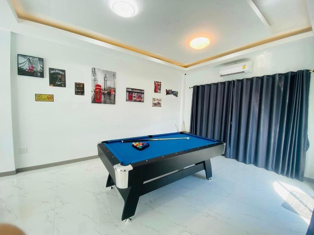 A pool table in a room with a white ceiling and walls, a black curtain, and various framed pictures on the wall.