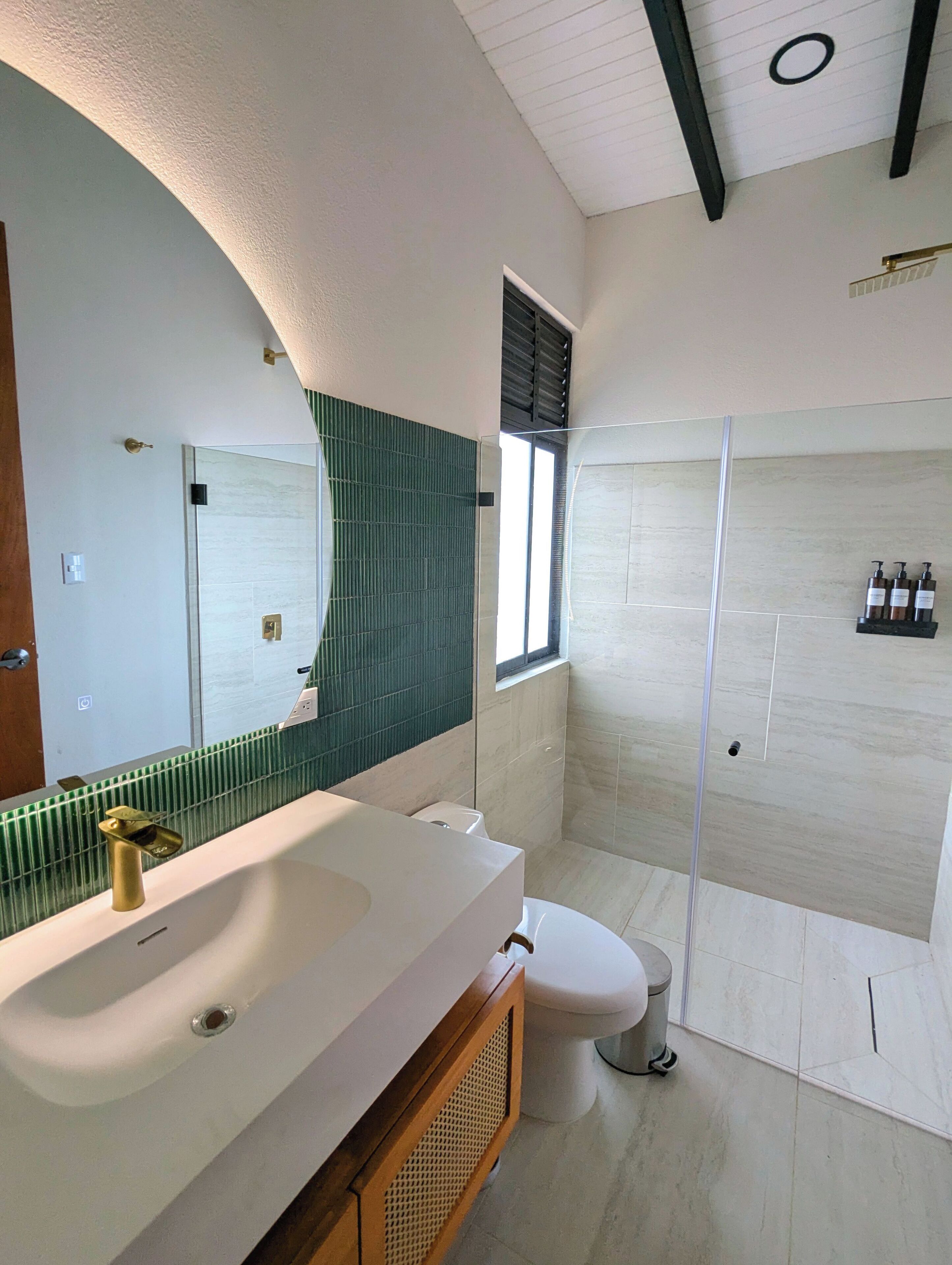 A modern bathroom with a large mirror, a sink, a toilet, and a shower area.