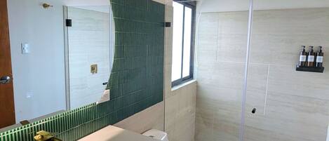 A modern bathroom with a large mirror, a sink, a toilet, and a shower area.