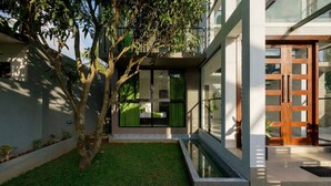 Une maison moderne avec une façade en verre, un petit jardin et une porte en bois.