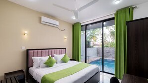 Une chambre d’hôtel moderne avec un grand lit, des rideaux verts, une vue sur une piscine et un ventilateur de plafond.