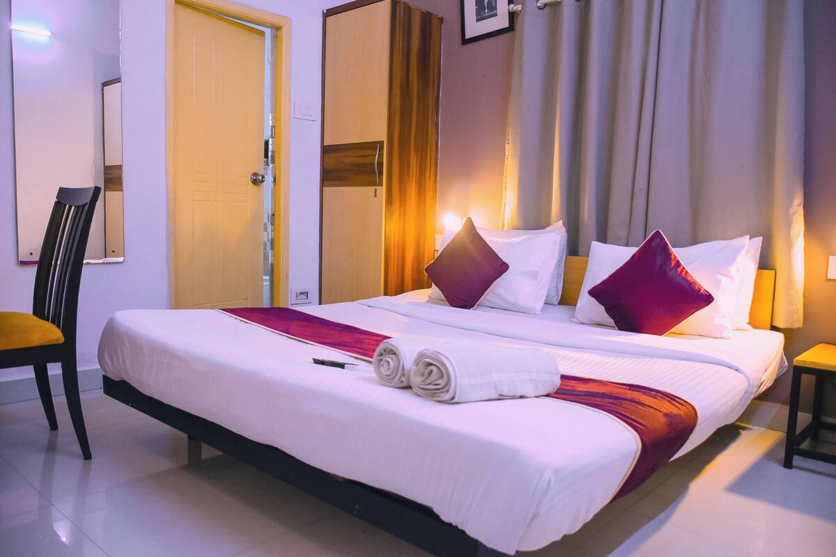 Ein Hotelzimmer mit einem großen Bett, einem Sessel, einem Kleiderschrank und einem Spiegel.