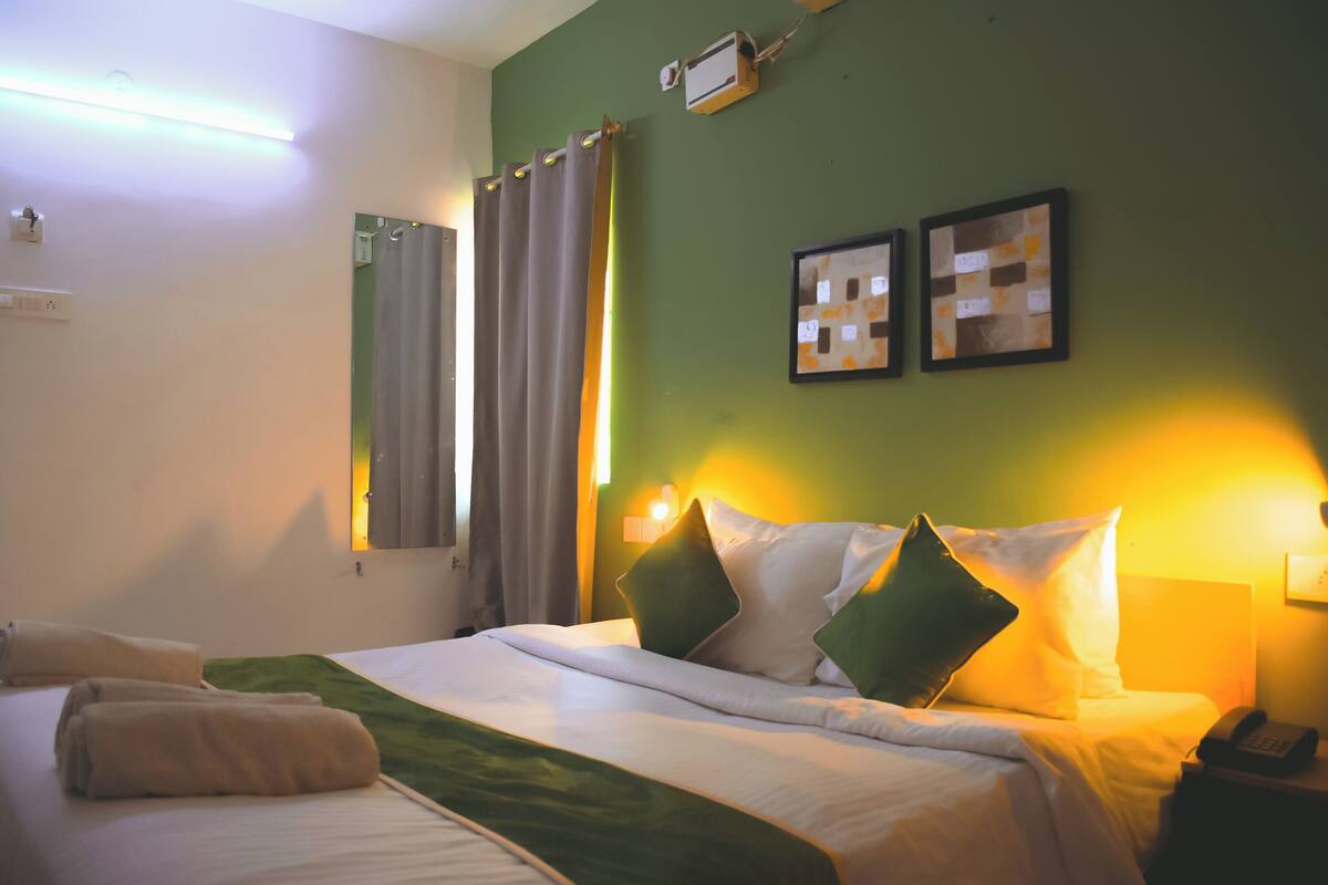Ein Hotelzimmer mit einem Bett, einem Nachttisch, einem Telefon und einer Wand-Klimaanlage.