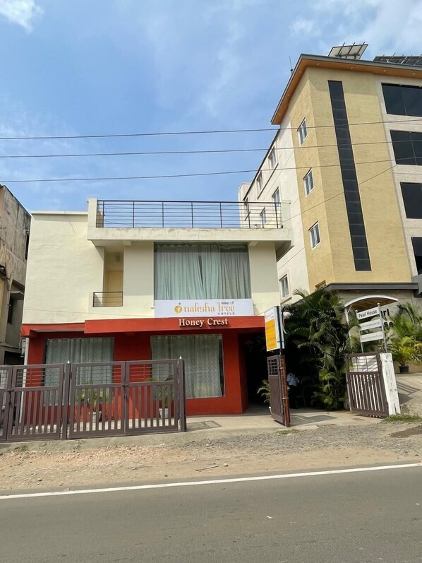 A hotel named "Honey Crest" with a signboard, a gated entrance, and a building adjacent to it. - Naksha Tree Hotels Honey Crest (Chennai)