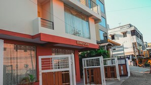 A building named 'Honey Crest' with a red facade, large windows, and a gated entrance. - Naksha Tree Hotels Honey Crest (Chennai)