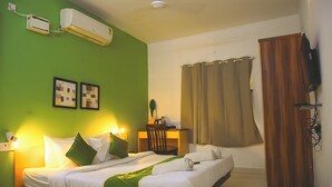 A hotel room with a bed, a desk, a chair, an air conditioner, and a television. - Naksha Tree Hotels Honey Crest (Chennai)