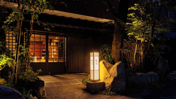 A traditional Japanese building with a wooden exterior, a tiled entrance, and a stone lantern. - Yusai Bekkan (Minamioguni)