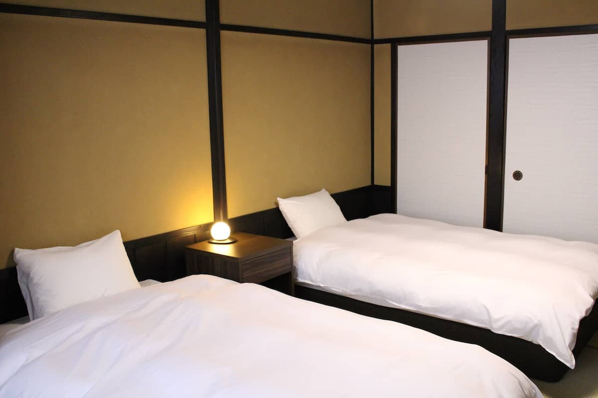 Una camera d'albergo con due letti singoli, un comodino con una lampada e un armadio.